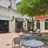 a courtyard with tables, chairs and a tree